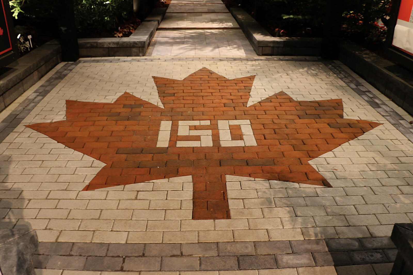interlocking stone with a red maple leaf pattern and 150 in the centre