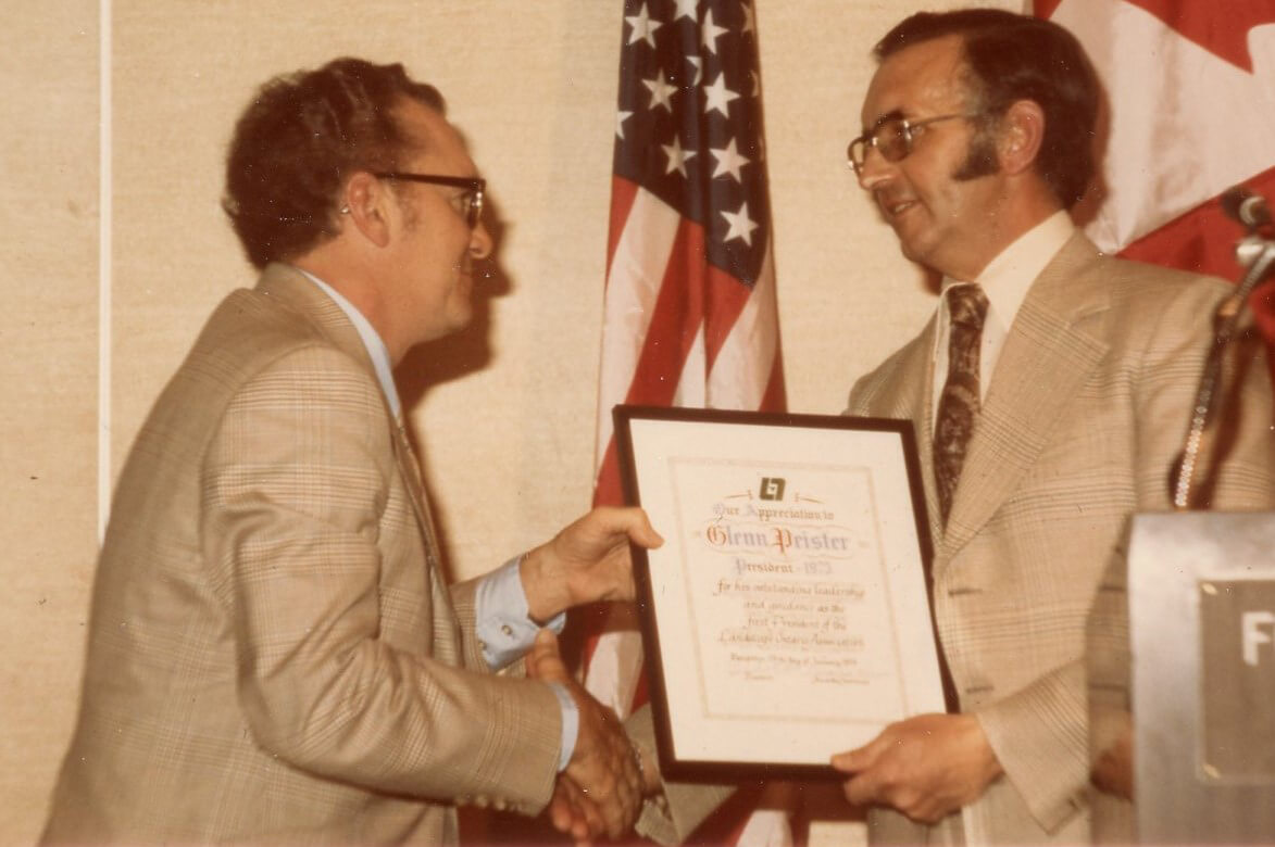 old photo of a man accepting a certificate from another man